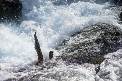 High angle view of waves splashing on rocks in sea