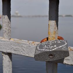 Close-up of padlocks hanging on railing with river in background