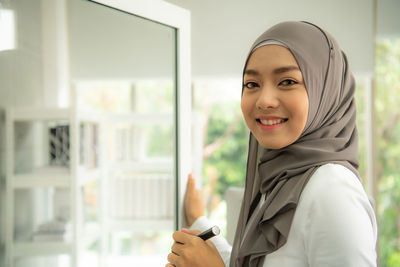 Portrait of smiling woman standing at home