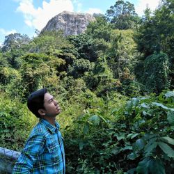 Side view of man looking away against trees