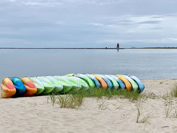 Multi colored kayaks on beach against sky