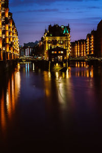 Illuminated buildings by river at night