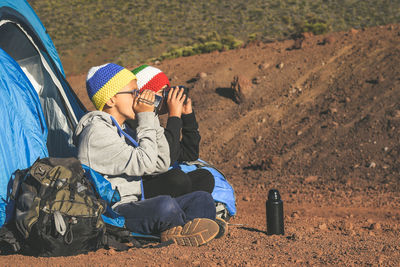 Brothers drinking coffee while camping on land