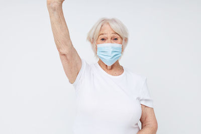 Portrait of young woman wearing mask against white background