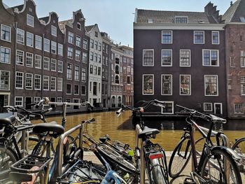 Bicycle parked by canal against buildings in city