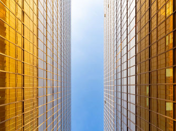 Directly below modern glass building in city against sky