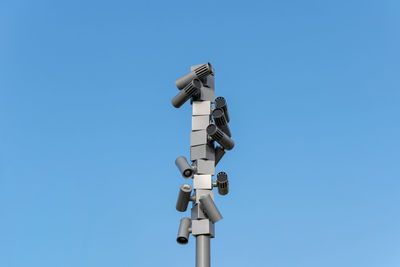 Low angle view of telephone pole against clear blue sky