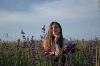 Portrait of young woman standing on field against sky