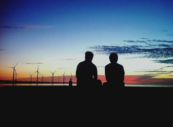 Silhouette of friends against sky