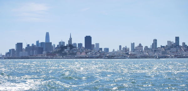 Sea by buildings against sky in city