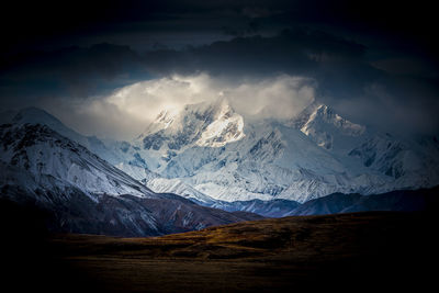 Scenic view of snowcapped mountains against cloudy sky