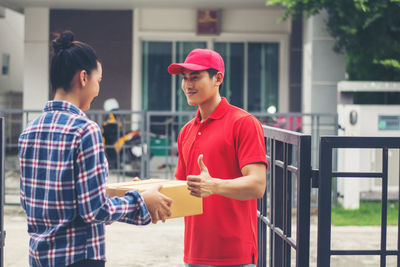 Man delivering package to female customer at gate