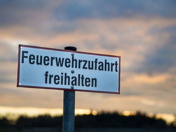 Close-up of road sign against sky