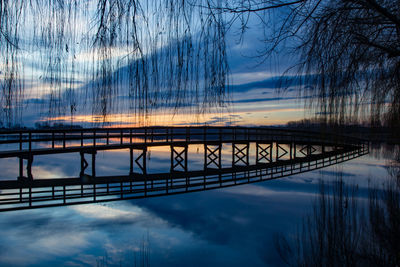 Silhouette bridge over lake against sky during sunset