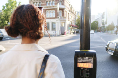 Woman waiting by pedestrian crossing button