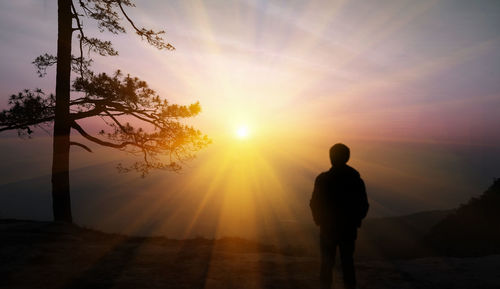 Rear view of silhouette man standing against sky during sunset