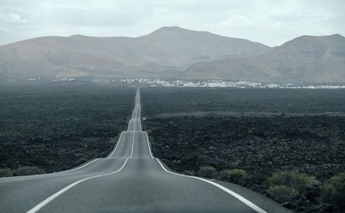 Road leading towards mountains against sky