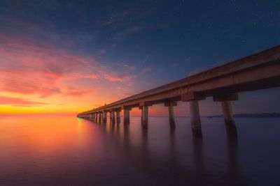 Pier over sea against sky during sunset