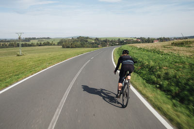 Rear view of man riding bicycle on road