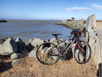 Bicycles on rock by sea against sky