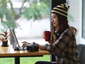 Side view of young woman using laptop on table