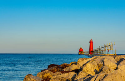 Golden sunlight of a summer morning shines on the red lighthouse at grand haven, michigan.