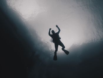 Low angle view of silhouette man scuba diving in sea