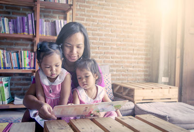 Mother showing book to daughters at home