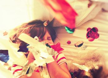 Girl lying on bed tossing confetti and laughing