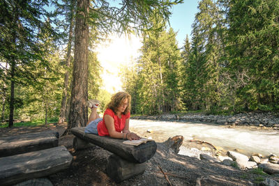 Teenage girl lying on wood in forest