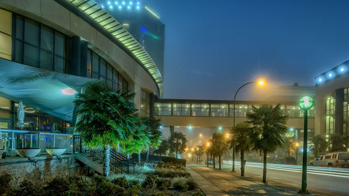 Illuminated street light in city against clear sky at night