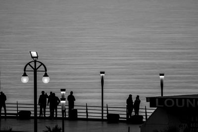 High angle view of silhouette people on bridge over sea