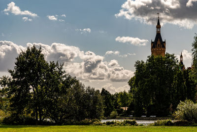 View of trees and building against cloudy sky