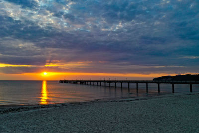 Pier over sea against sky during sunset