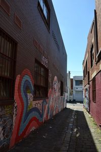 Graffiti on footpath amidst buildings against sky