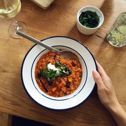 Cropped hand of woman holding lentil soup on wooden table