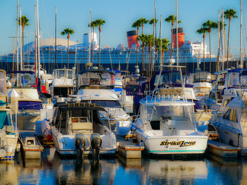 Boats moored at harbor against blue sky