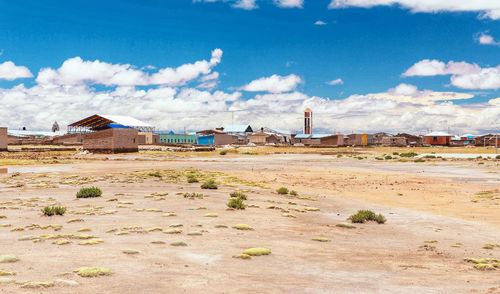 Houses on field by buildings against sky