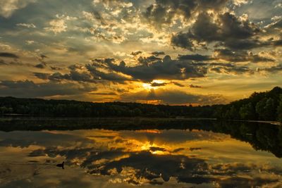 Scenic view of lake against dramatic sky during sunset