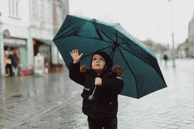 Young woman standing on wet street during rainy season