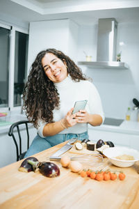 Portrait of smiling woman using phone at home