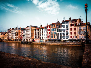 Canal by buildings against sky in city