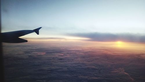 Airplane flying over cloudscape during sunset