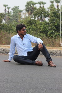 Portrait of young man sitting on road