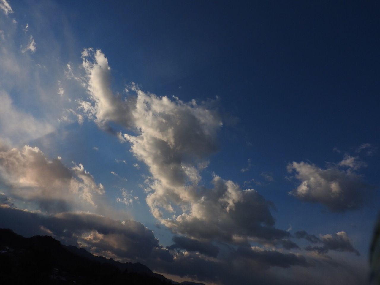 sky, tranquility, scenics, tranquil scene, beauty in nature, cloud - sky, low angle view, nature, silhouette, blue, cloud, idyllic, mountain, cloudy, cloudscape, outdoors, majestic, sunset, no people, sunlight