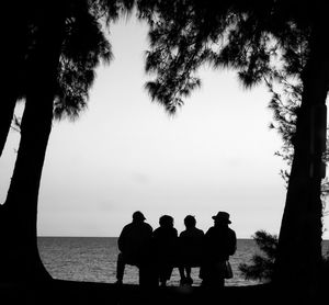 Silhouette people standing by sea against clear sky