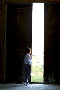 Side view of woman standing at doorway