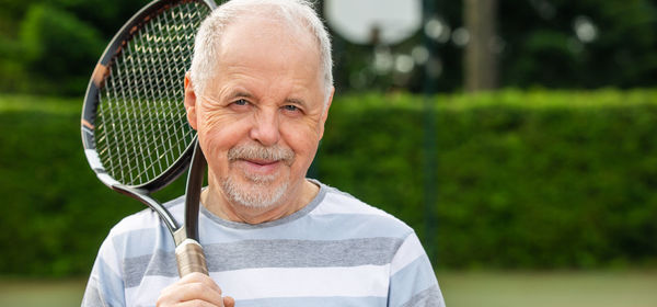 Portrait of man holding tennis racket outdoors