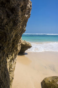 Rock formation on beach against sky