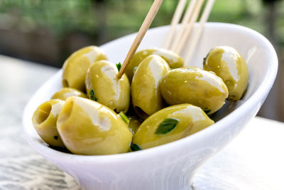 Close-up of green olives in bowl with toothpicks on table